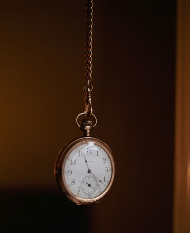 a-pocket-watch-hanging-from-a-chain-in-a-dark-room.jpg A pocket watch hanging from a chain in a dark room